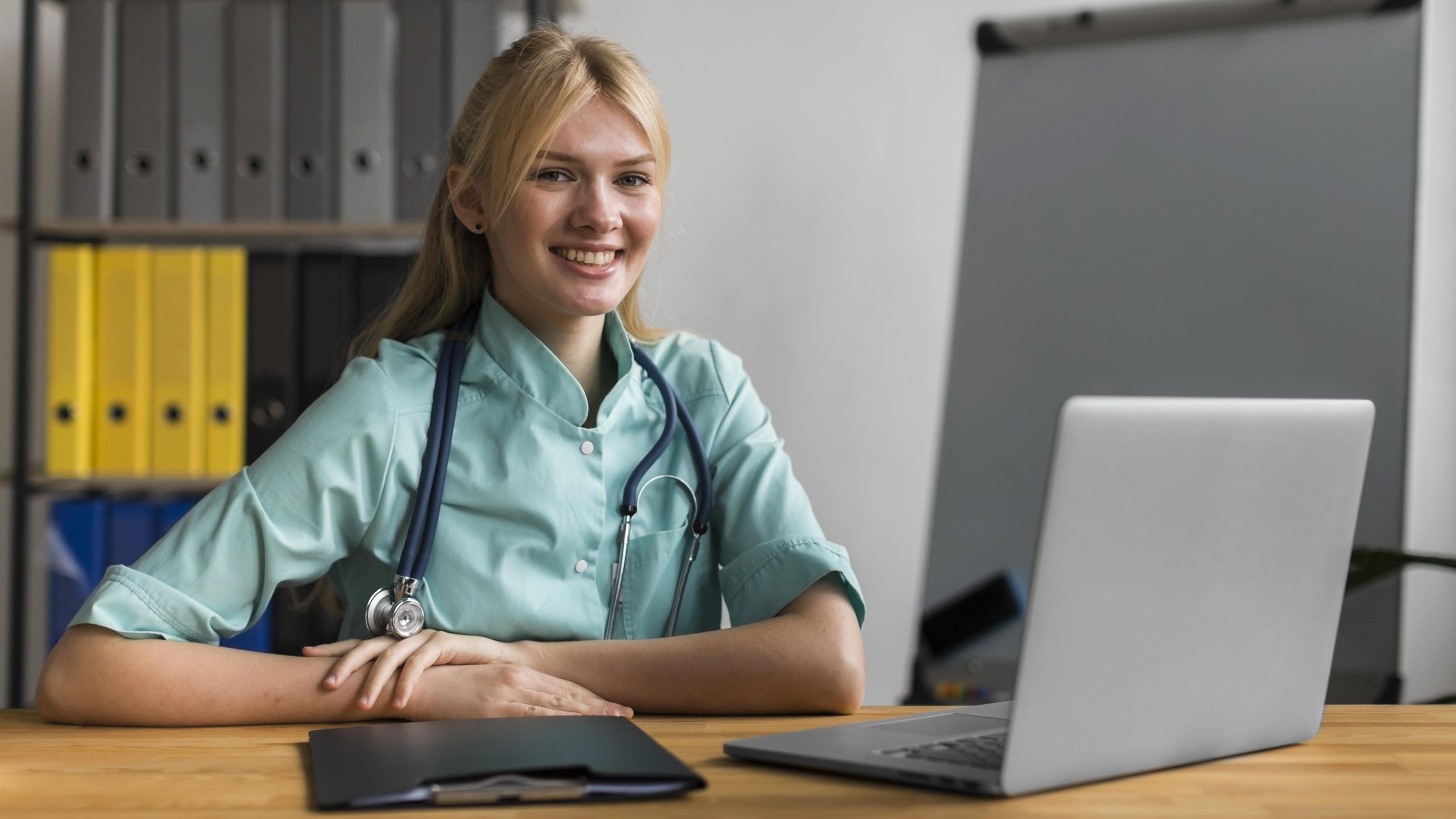 smiley-female-nurse-office-with-stethoscope-laptop